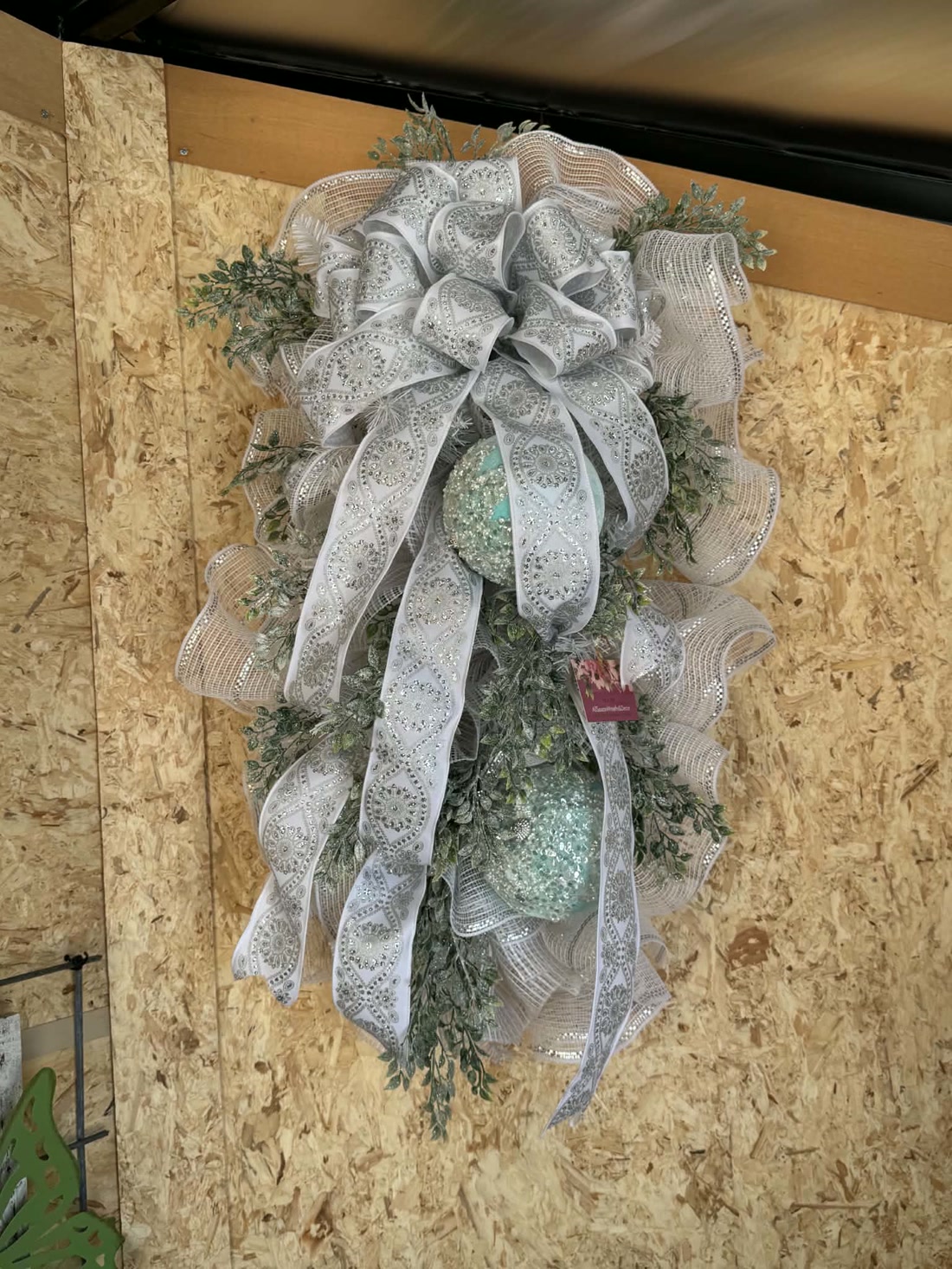 A silver lace-ribbon swag with frosted greenery and mercury-glass ornaments.