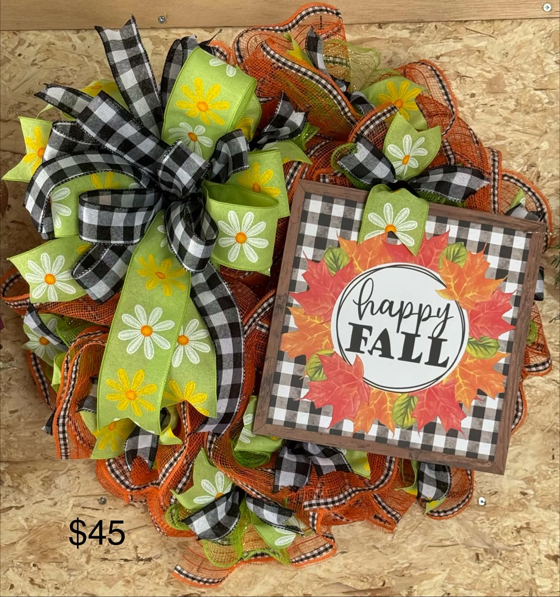 A 'Happy Fall' door wreath: orange and yellow blooms, autumn leaves, and a hand-lettered fall sign at the center.